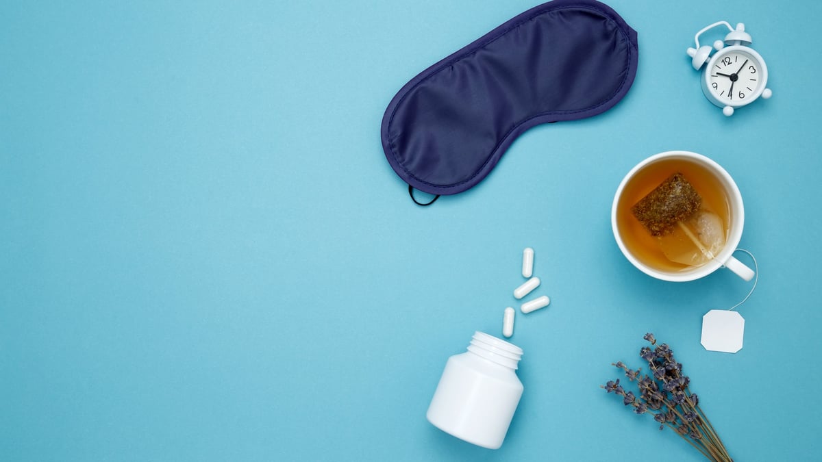 Concept of relaxation and rest, insomnia treatment. Sleep essentials eye mask, tea, pills, clock